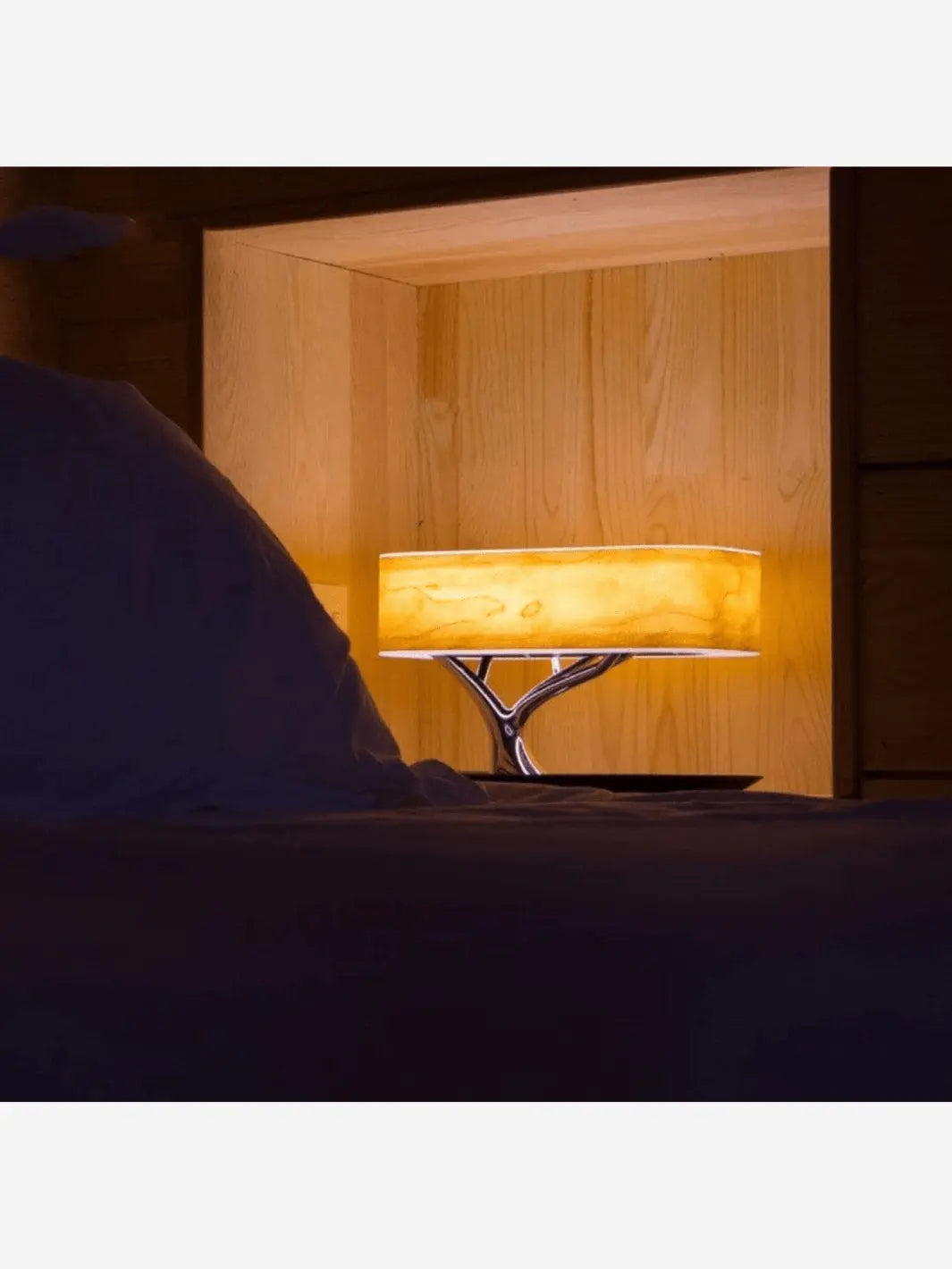 Lampe de chevet connectée moderne et originale en forme d'arbre qui éclaire une table de chevet dans une chambre