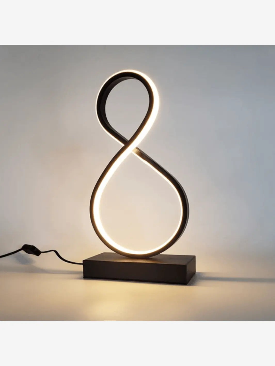 Lampe de chevet LED design original et moderne formant un huit de couleur noir qui éclaire une chambre
