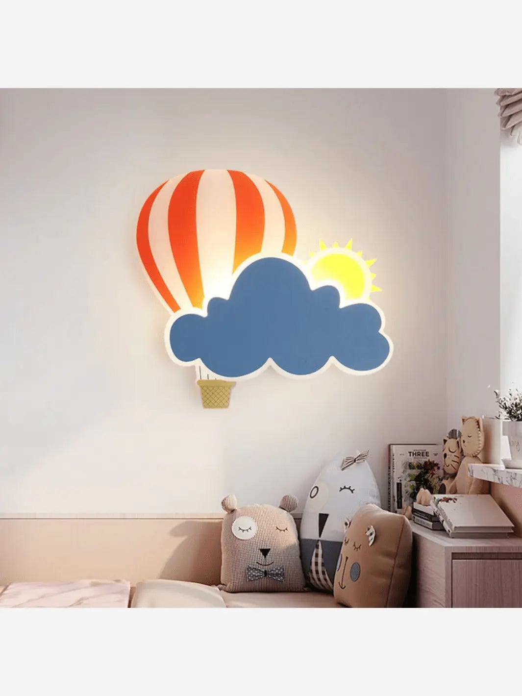 Lampe de chevet murale pour enfant qui représente un nuage, un soleil ainsi qu'une montgolfière au dessus un lit dans une chambre
