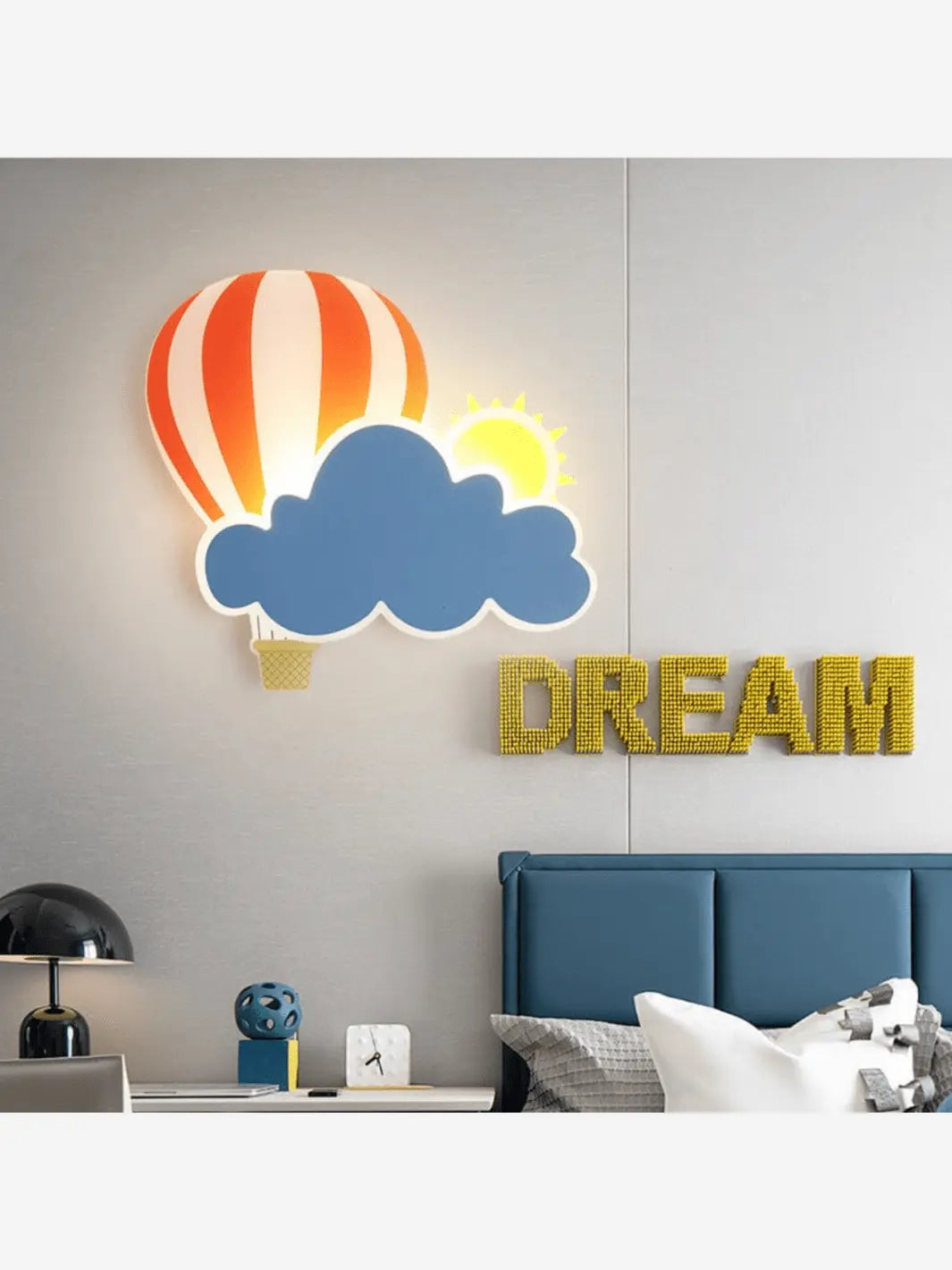 Lampe de chevet murale pour enfant qui représente un nuage, un soleil ainsi qu'une montgolfière au dessus un lit dans une chambre