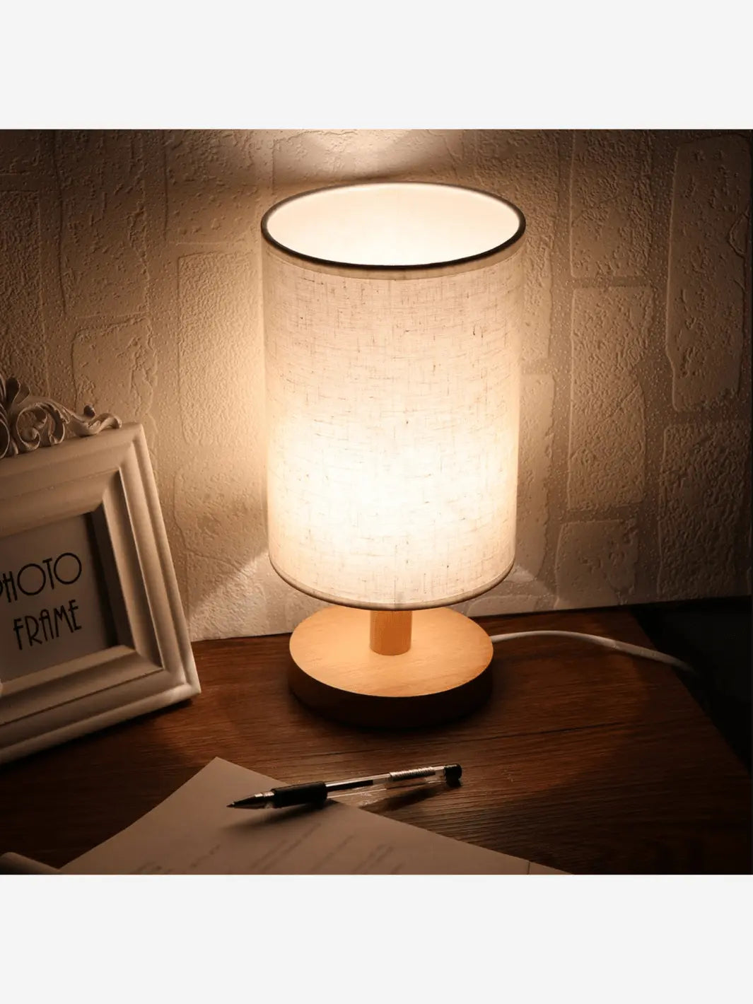 lampe de chevet scandinave avec pied en bois et abat jour en tissu clair posee sur une table de chevet