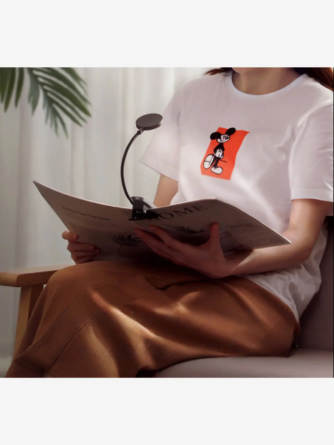 personne qui lit avec une lampe de lecture clipsee sur son livre