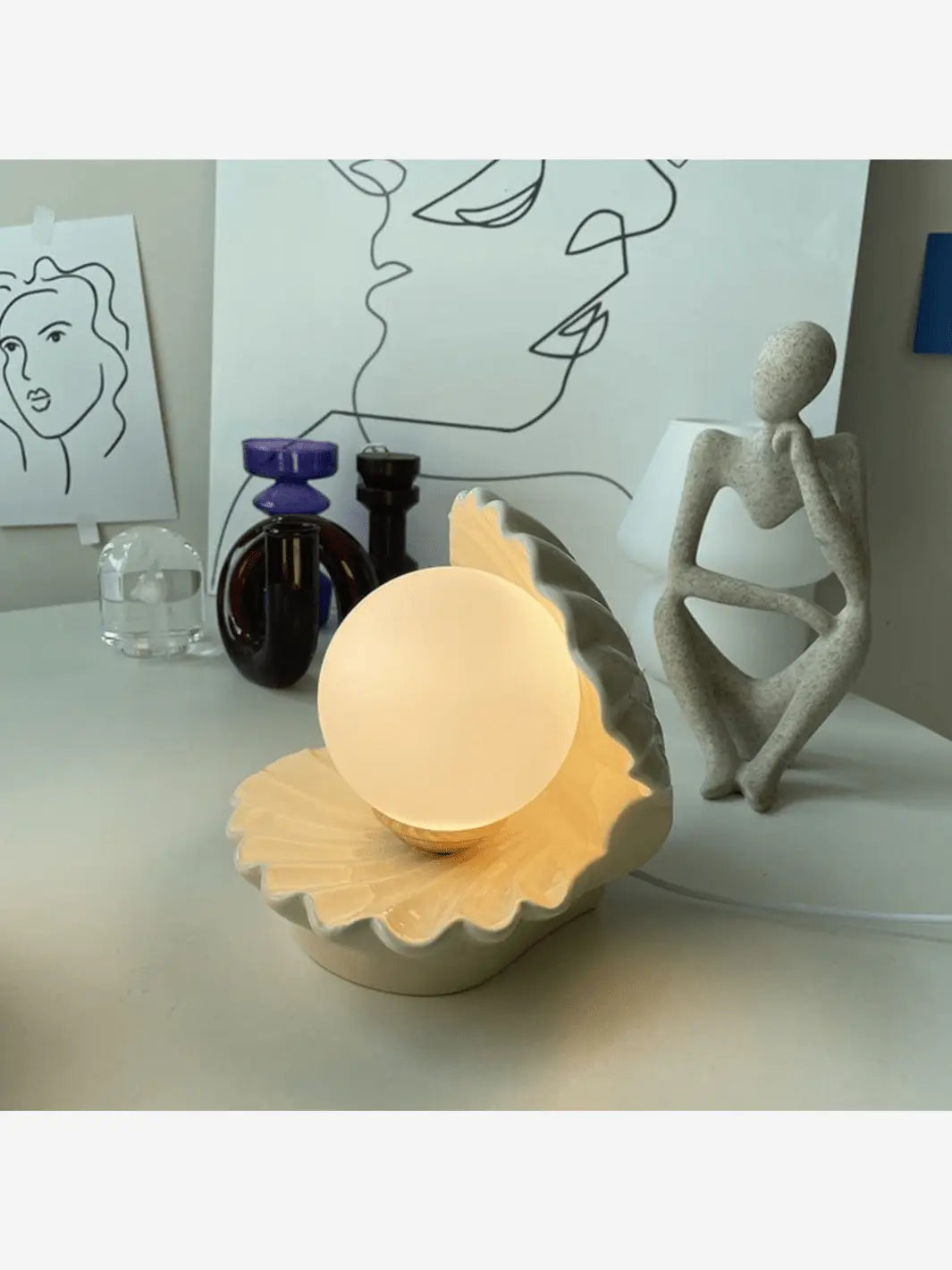 lampe de chevet en ceramique en forme de coquillage qui s ouvre sur une perle qui s allume design moderne sur un bureau avec une jolie statuette decor moderne