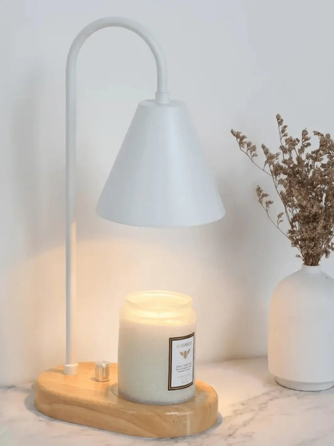 lampe de chevet chauffe bougie avec abat jour blanc et socle en bois sur lequel on pose une bougie qui fond grace a la lumiere de la lampe posee sur une table de chevet en marbre 