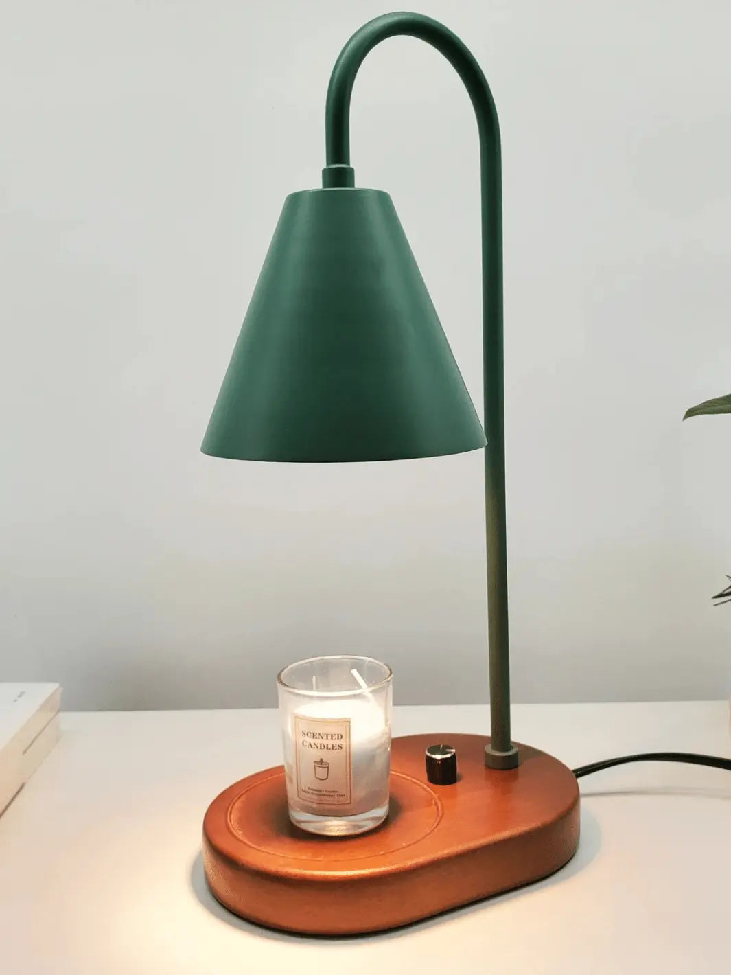lampe de chevet chauffe bougie avec abat jour vert foret et socle en bois sur lequel on pose une bougie qui fond grace a la lumiere de la lampe posee sur une table de chevet