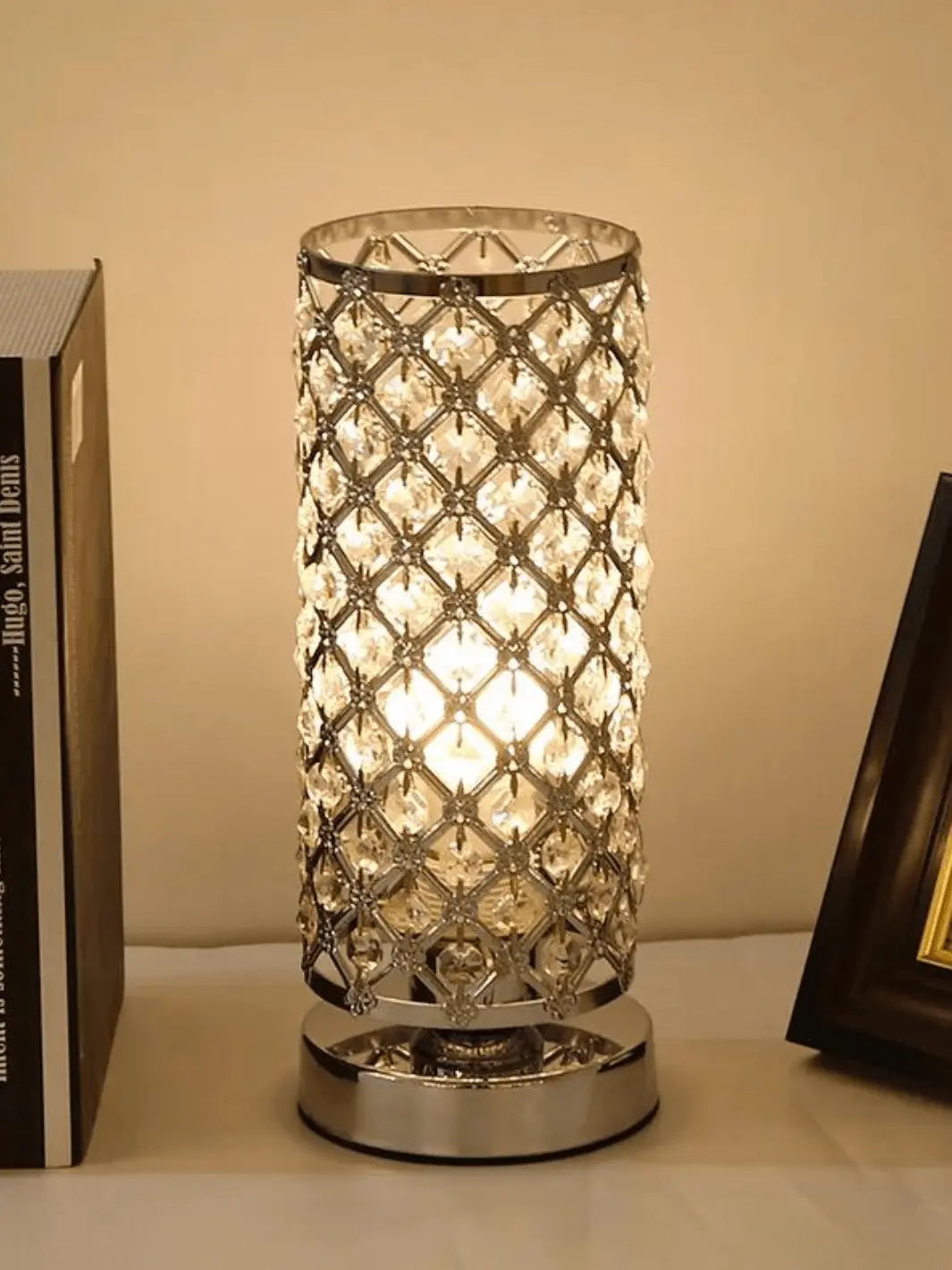 lampe de chevet cristal en argent allumee posee sur une table de chevet
