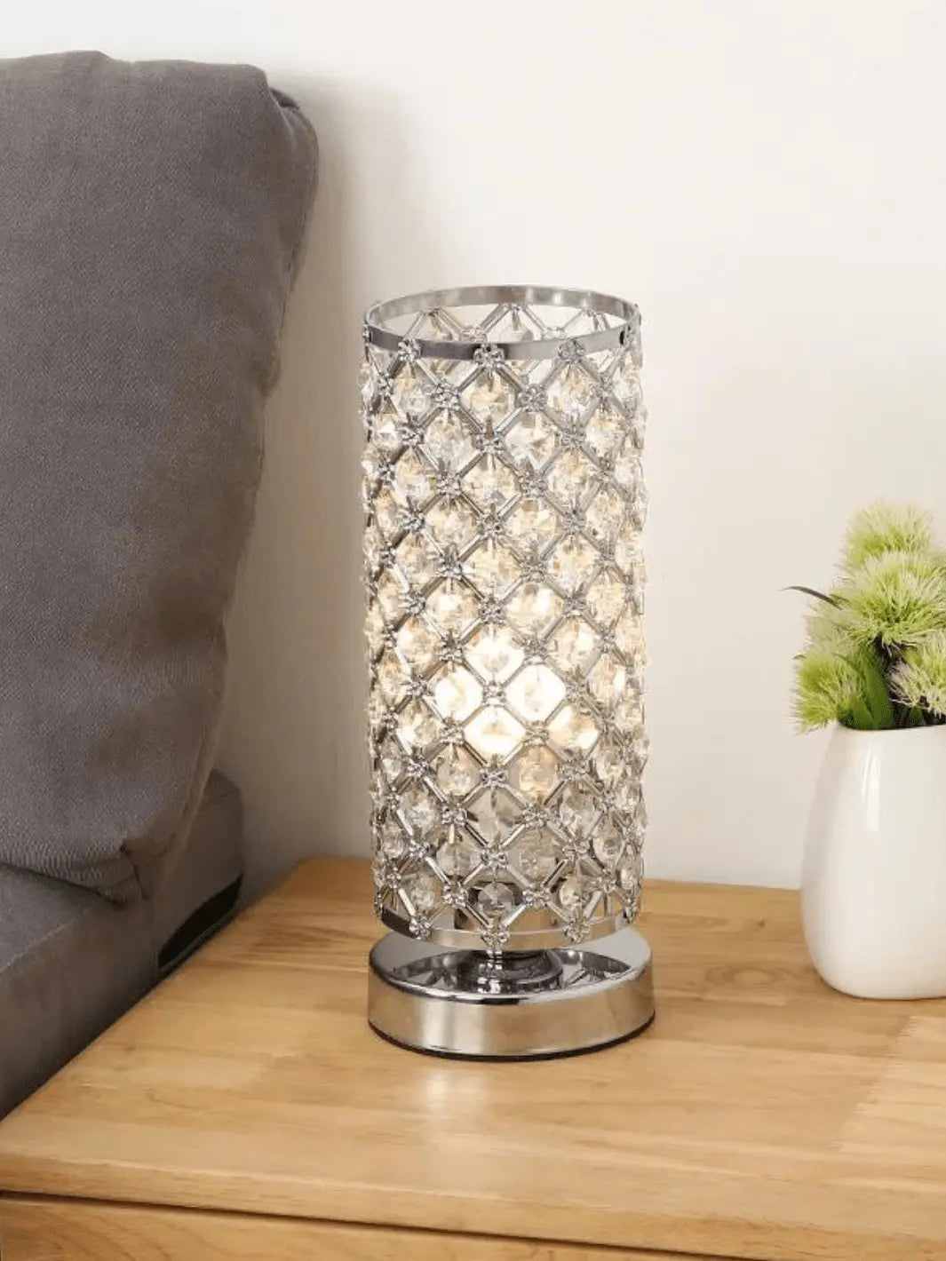 lampe de chevet cristal en argent avec base en metal posee sur une table de chevet en bois