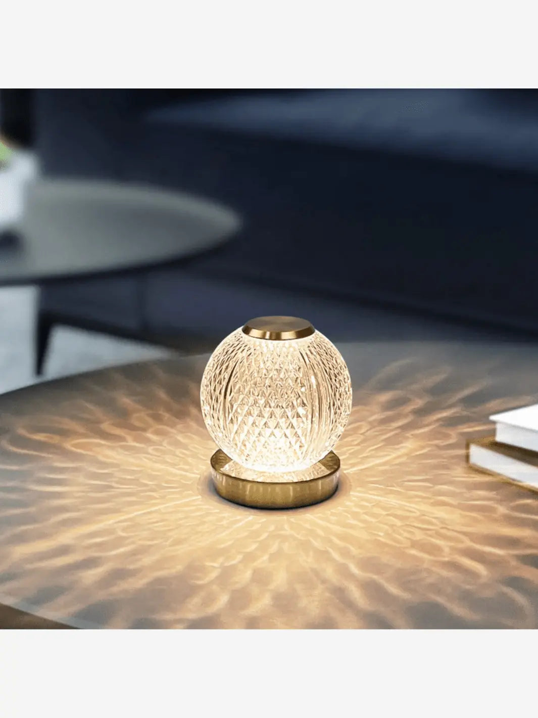 lampe de chevet representant une boule en cristal allumee posee sur un socle couleur or