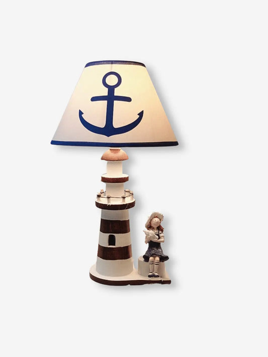 lampe de chevet en bois representant un phare avec une encre sur l abat jour et une petite fille qui lit a son pied