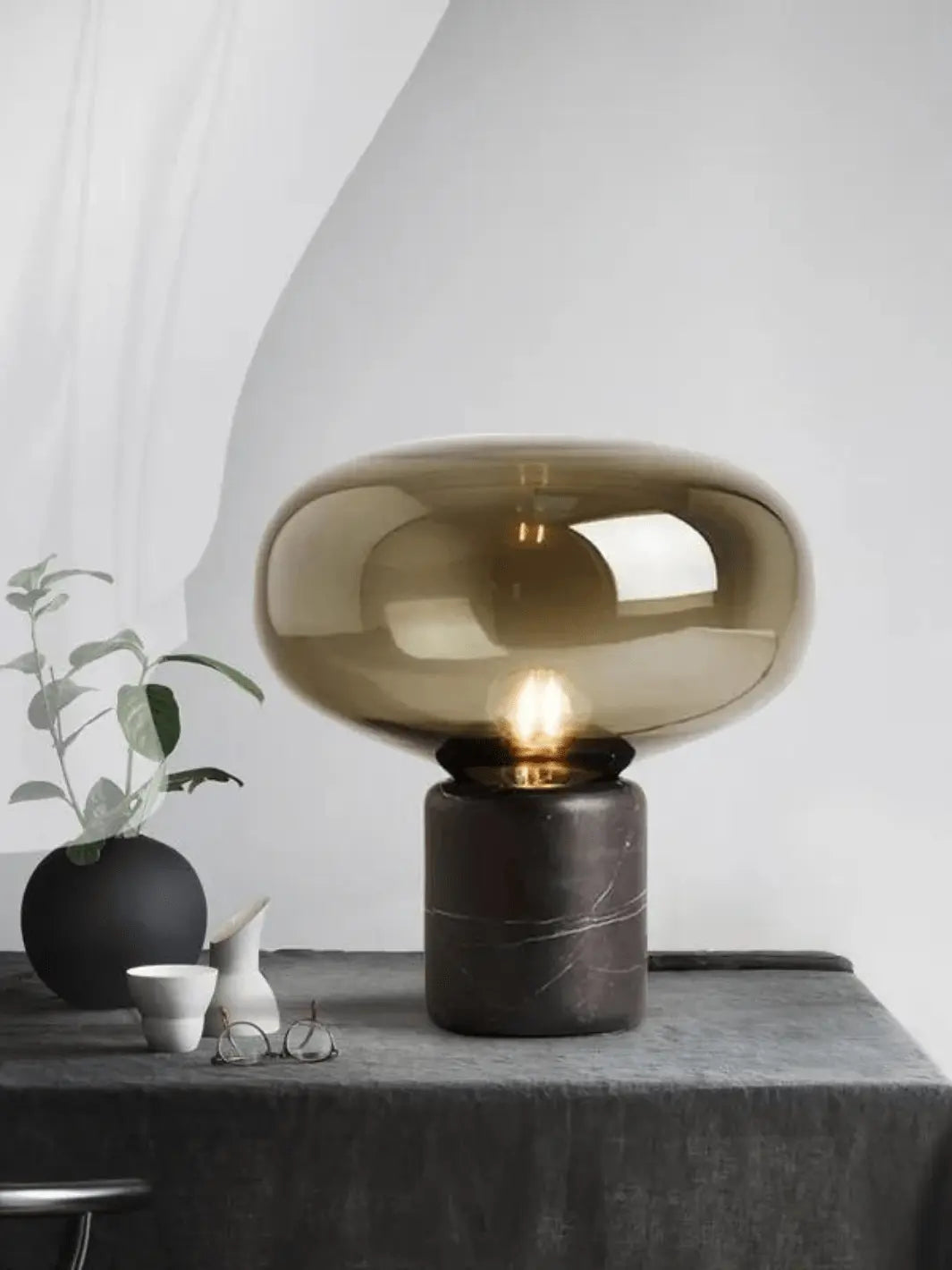 lampe de chevet en marbre noir avec abat jour ambre fumee posee sur une table de chevet design minimaliste moderne