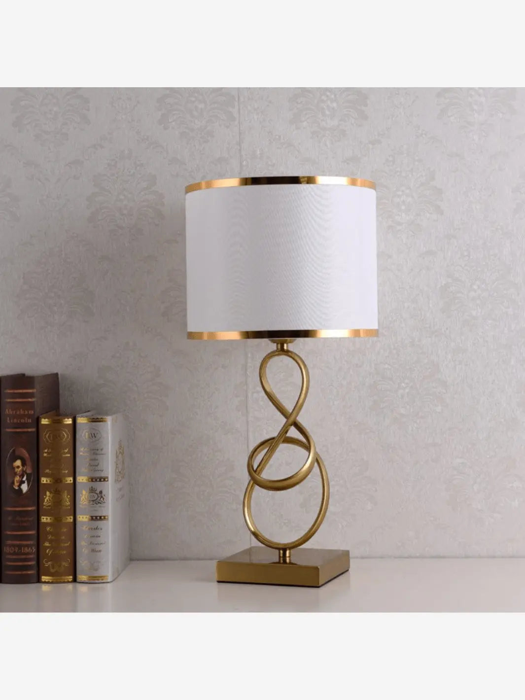 lampe de chevet luminasculpt doree et blanche posee sur une table de chevet avec des livres en deco originale design et moderne