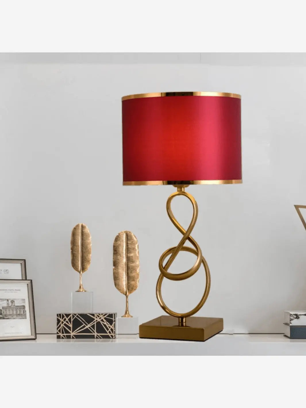 lampe de chevet design moderne et a la forme originale abat jour rouge pied or posee sur une table decoree