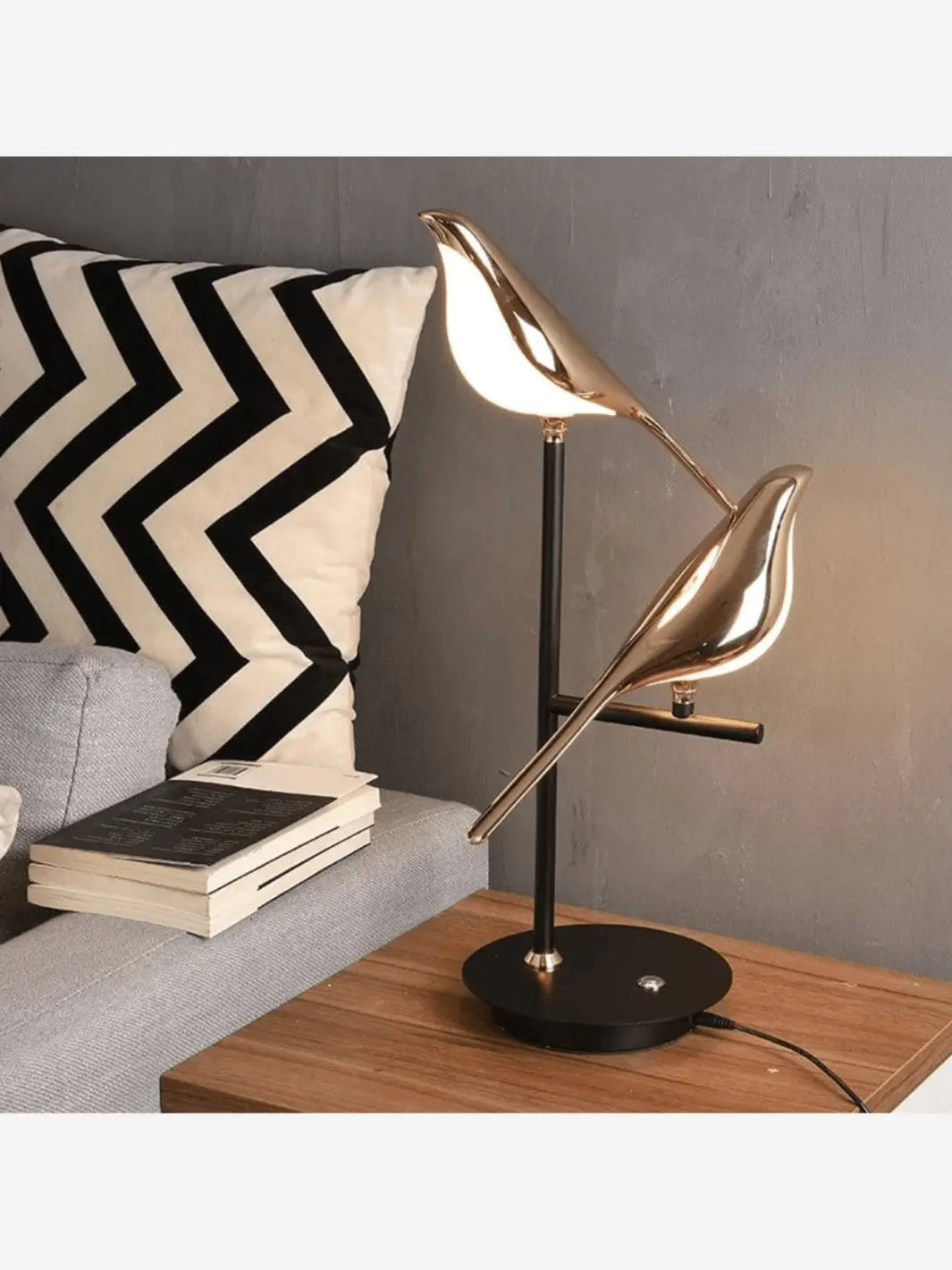 table de chevet bois avec une lampe de chevet formant deux oiseaux couleur doree perches sur une branche 