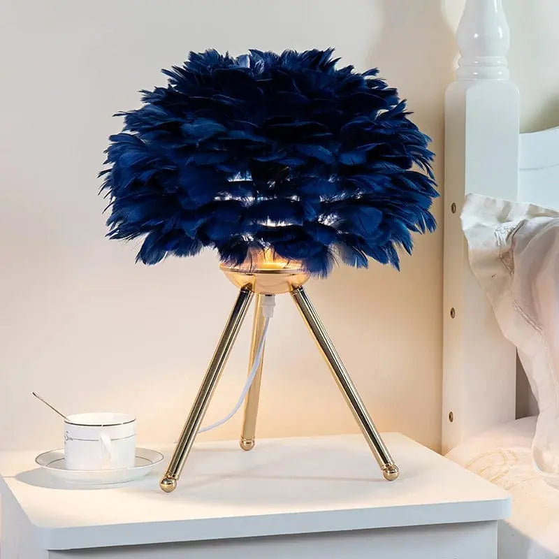 lampe de chevet sur pied avec abat jour en plumes bleu nuit et pieds couleur or design cozy et cocooning posee sur une table de chevet