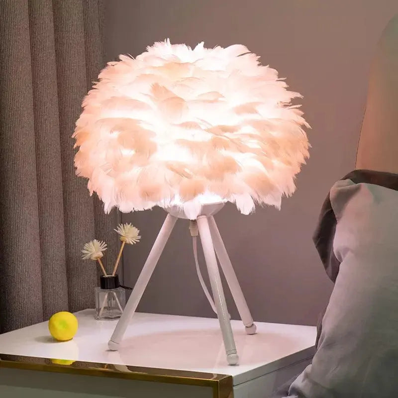 lampe de chevet sur pied avec abat jour en plume roses pastel et pieds couleur blanc design cozy et cocooning posee sur une table de chevet blanche
