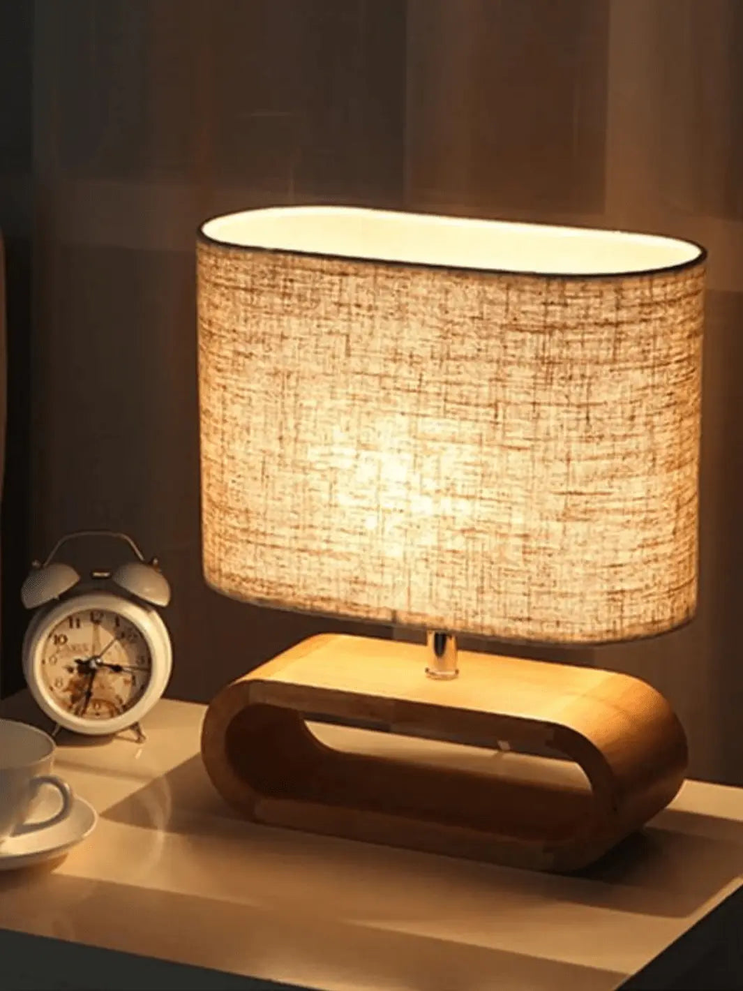 lampe de chevet scandinave avec abat jour en tissu et un pied en bois clair moderne et cozy posee sur une table de nuit a cote d un reveil