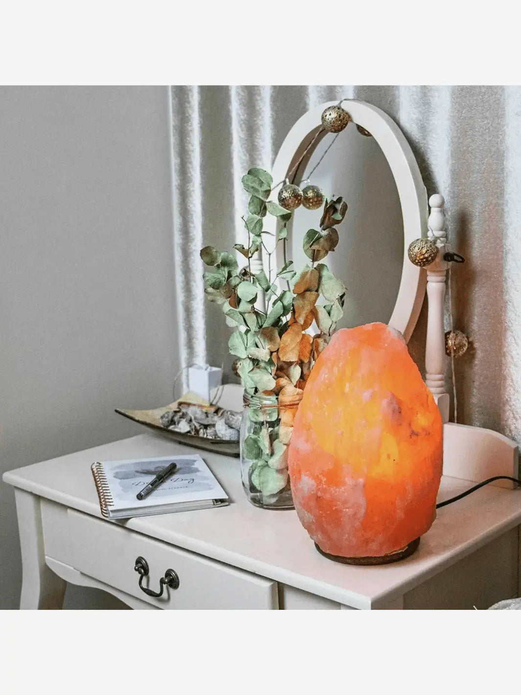 lampe de sel de l himalaya avec une grosse pierre de sel qui s illumine sur un socle en bois allumee et posee sur une coiffeuse bureau